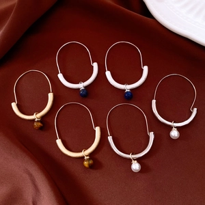 Three pairs of vintage hoop earrings with tiger eye, pearl and lapis on silk background