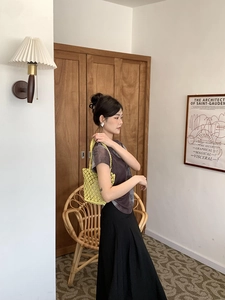 Model wearing bright yellow hand-woven bucket bag against a vintage wooden background