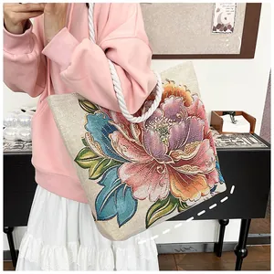 Shoulder shot of a canvas tote bag with embroidered peony flowers and white rope handles