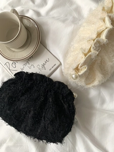 Détail d'une pochette en dentelle à texture plume et élégante fermeture perle