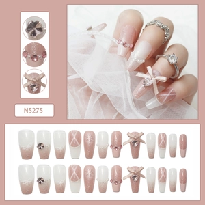 Close-up of pink gradient press-on nails with glitter, heart crystals, and bow details