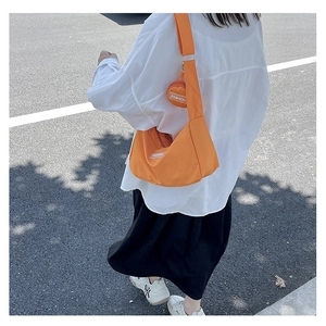 Outdoor shot of the orange nylon tote bag with small coin purse on a wide shoulder strap