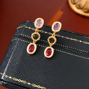 Vintage gold-plated earrings with purple green and red oval stones on black jewelry box