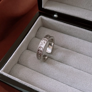 Detailed view of silver open ring with wheat grain texture in a premium velvet box