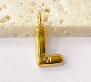 Detailed close-up of a golden puffy letter L pendant with sunburst engraving on stone