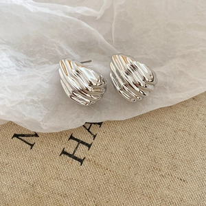 Detailed view of silver wave-patterned earrings on rustic natural fabric background