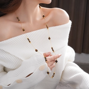 Détail du collier de pierre œil de tigre ronde sur modèle en pull blanc