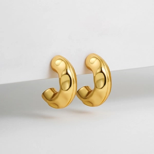 Macro view of thick C-shape golden earrings with high-gloss metallic finish