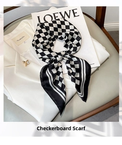 Detail of a black and white checkerboard silk scarf styled on a white blazer