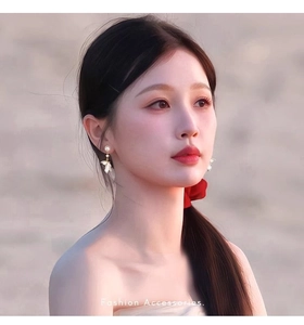Detail of floral wing earring with white pearl and gold finish on female model