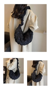 Quilted black crescent moon bag with cloud shoulder strap shown on a beige trench coat