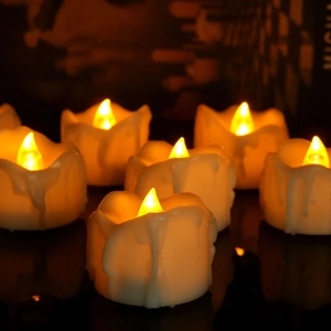 Detail of warm yellow LED electronic candles with dripping wax design on dark surface