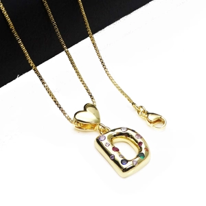 Macro detail of gold-plated D-letter pendant with colorful zircons on box chain