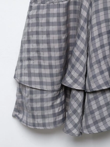 Macro detail of grey plaid fabric showing multi-layered ruffle design and texture