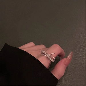 Detailed view of silver bow-shaped ring with transparent crystals on a hand model