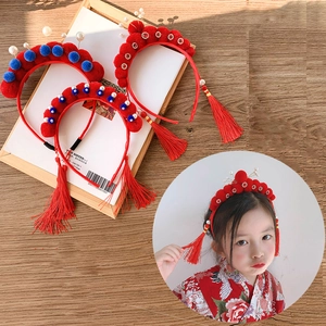 Detailed close-up of plush cat ear headband with red pom-poms, pearls and fringe tassels