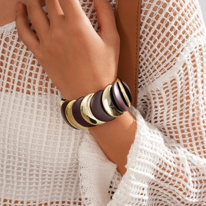 Dettaglio di un bracciale largo in acrilico con metallo dorato e segmenti in resina bordeaux