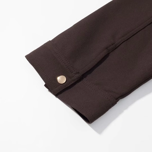Detailed close-up of coffee brown sleeve cuff with a polished gold metallic button