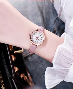 Detail of rose gold watch with roman numerals on a pink leather strap worn by a model