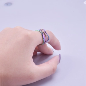 Close-up of rainbow layered wavy ring in golden finish on a hand
