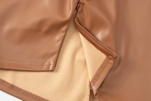 Detail view of caramel brown PU leather top featuring metallic zipper and fleece lining texture