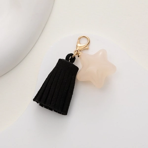Detail of a black tassel and beige star pendant keychain with a golden metal clasp