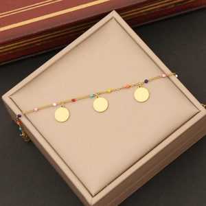 Détail d'un bracelet en chaîne dorée avec perles colorées et pendentifs sur écrin