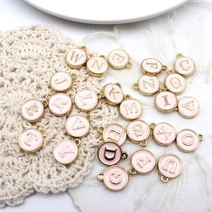 Pink enamel round alphabet charms with gold plating on white lace background
