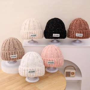 Detail of colorful polka dot knit beanies with smiling face patch in six assorted colors