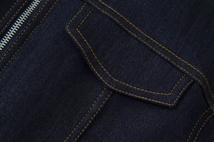 Gros plan détaillé du tissu denim bleu foncé avec coutures jaunes et zip métallique