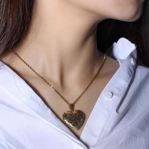 Gros plan d'un collier médaillon coeur doré avec gravure florale sur un mannequin