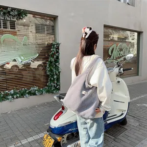 Grey sherpa tote bag with white woven label shown in an outdoor street style setting