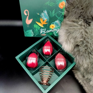Detail of red makeup sponges in clear cases with a rose gold stand in a green gift box