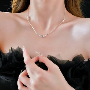 Close-up of silver bow necklace with elegant metallic finish on a female model