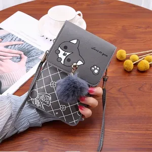 Close-up of grey mini crossbody bag with husky embroidery and plush ball on wooden table