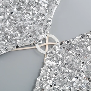 Detail of silver sequin evening dress featuring a white resin ring and slim straps