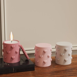 Detailed view of Morandi-colored candle jars with heart-shaped relief on a wooden table