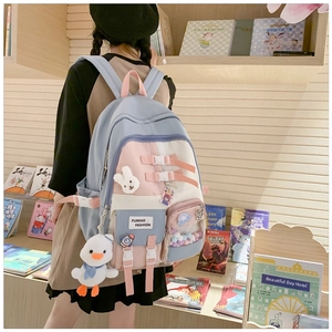 Detail of blue and pink school backpack featuring cute plush charms and multiple pockets