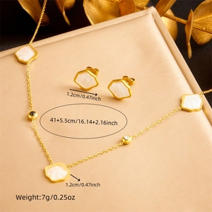 Gold-plated shell clover necklace and earrings set with crystal details on beige background