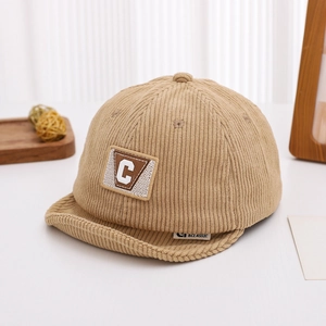 Detail of baby corduroy cap featuring a letter C patch and soft warm fabric texture