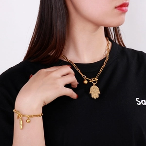 Golden Hamsa hand charm and paperclip link chain jewelry set worn by a model