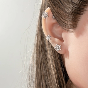 Silver snowflake ear stud set on model showing minimalist winter holiday ear jewelry
