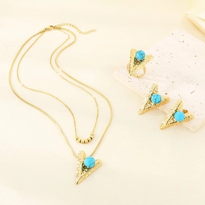 Detail of gold jewelry set with turquoise inlay heart pendants on textured stone