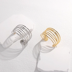 Detailed view of gold and silver multi-layer wide cuff bracelets on stone pedestals