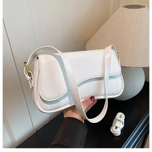 Detail of white leather shoulder bag featuring metal buckle and textured finish