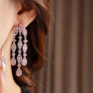 Detail of silver drop earrings with pink zircon tassels worn by a model in a profile view