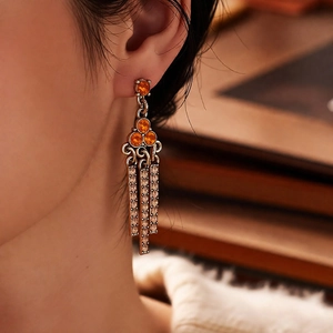 Close-up of vintage triangle tassel earrings with amber gems and diamond chains on a model