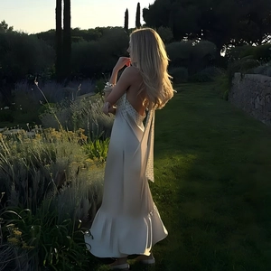 Detail view of white halter neck satin dress featuring elegant backless design and ruffles