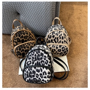 Three leopard print mini backpacks in different colors on a soft brown velvet carpet