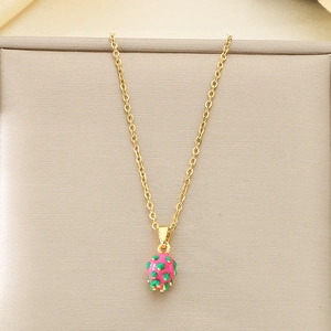 Close-up of a golden fruit pendant necklace featuring a dragon fruit in pink and green